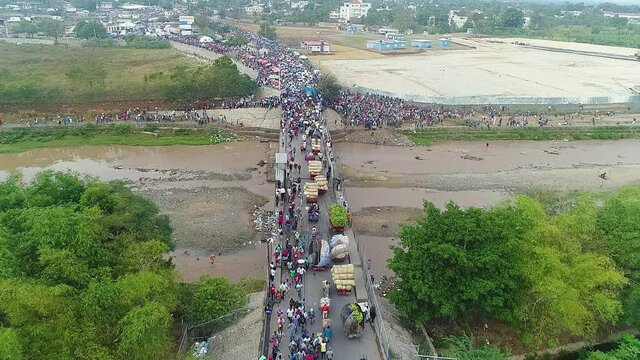 Aerial, drone shot overlooking traffic and a lot of people on a bridge, at the border between the Dominican republic and Haiti