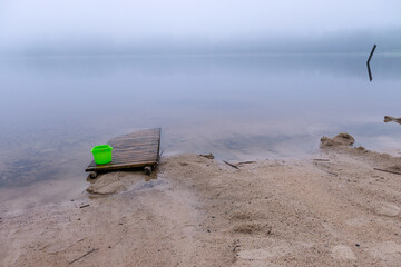 Fototapeta na wymiar sandy beach after heavy rain, white fog on the lake, fuzzy contours