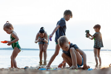 mom tries to photograph children, children play on the beach near the water, summer, family vacation