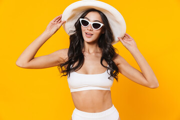 Image of woman in swimsuit and hat smiling and posing at camera