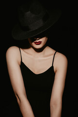 Fototapeta na wymiar stylish Studio portrait of a girl in a black hat and dress