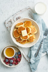 Pancakes cereal, tiny thin funny crumpet, children's food. Breakfast with drink, white table