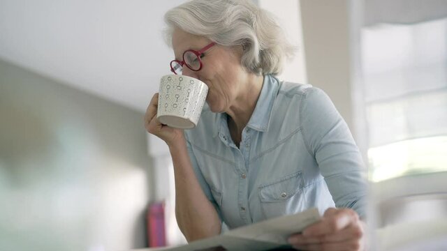 Portrait of senior woman reading newspaper