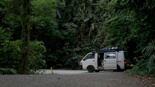 Camper van parking on dirt road in tropical rainforest. Dense jungle