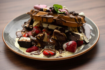 Delicious waffles with fresh fruits, ice cream, strawberry, colorful candy, different toppings - sweet food