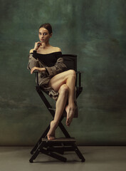 Beautiful portrait. Graceful classic ballerina dancing, posing isolated on dark studio background. Stylish trench coat. Grace, movement, action and motion concept. Looks weightless, flexible.