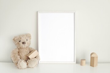 White frame mock up for photo, print art, text or lettering, with nursery  toys. Blank frame on white table.
