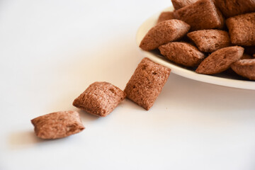 Closeup view of three crispy brown Cereal pillows on side and white plate with Cereal pillows on white background
