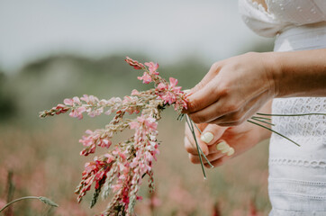 Woman hands braiding wild flowers into a flower crown