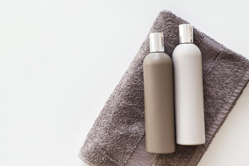 Plastic bottles of shampoo and body gel on towel isolated on white. Flat lay