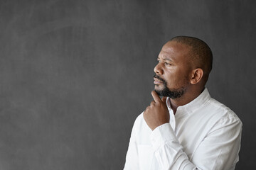 African American businessman standing by a chalkboard deep in thought