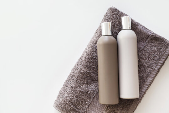 Plastic bottles of shampoo and body gel on towel isolated on white. Flat lay