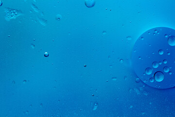 Abstract blue background with oil drops and waves on water surface