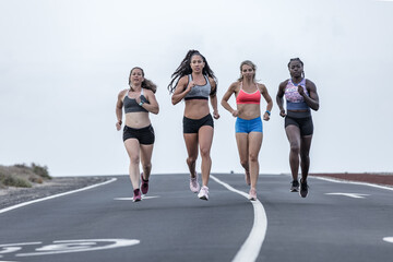 Multiethnic female runners on road in outskirts
