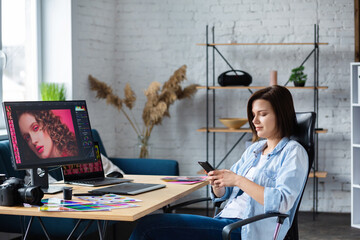 Portrait of graphic designer working in office with laptop,monitor,graphic drawing tablet and color palette.Retouching images in special program.Retoucher workplace in photo studio.Creative agency.