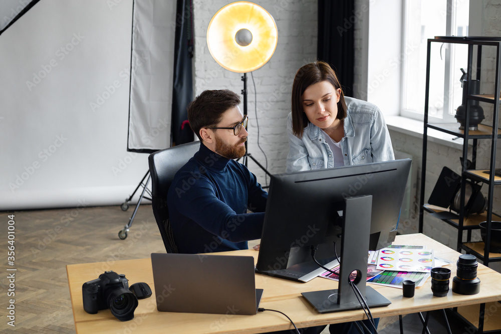 Poster Photographer and graphic designer working in office with laptop, monitor, graphic drawing tablet and color palette. Creating team discussing ideas in advertising agency. Retouching images. Teamwork.