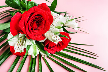 Bouquet of red roses with white flowers on a pink background.