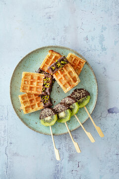 Kiwi am Stiel und Waffeln mit Kardamom-Schokolade, Pistazien und Sesam