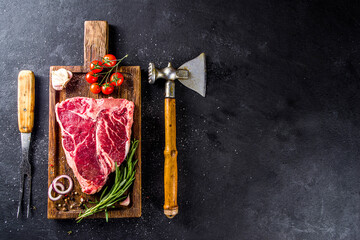 Cooking meat background. Raw aged beef t-bone steak, with spices and herbs for cooking on a gray table background top view