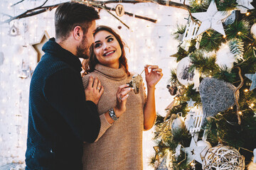 Happy caucasian couple in love having fun together near beautiful Christmas tree 