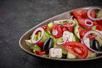 Fresh greek salad in plate on the black background.