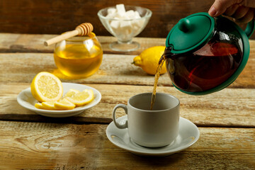Fresh tea from the teapot is poured into a white cup.