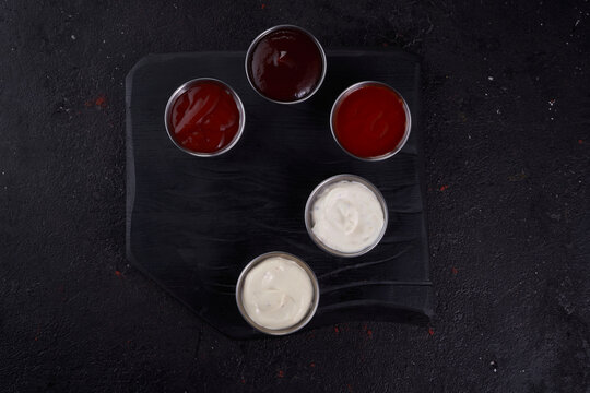 Set of sauces on dark wood background.