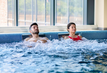 Couple relaxing in indoor swimming pool at hotel resort.