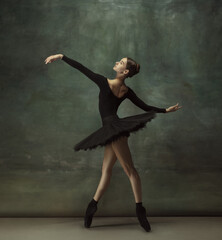 Passioned. Graceful classic ballerina dancing, posing isolated on dark studio background. Elegance...