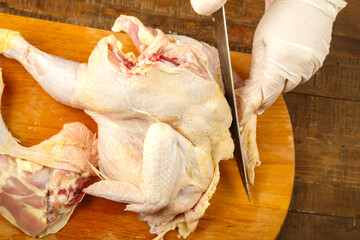 A female hand cuts off chicken pieces with a sharp knife. © finist_4