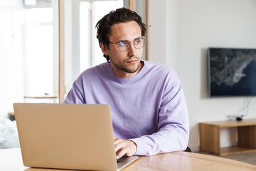 Attractive young man sitting at the kitchen table