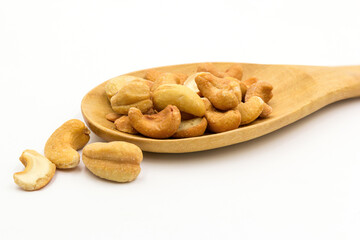Roasted salted cashew nuts on wooden ladle isolated on white background