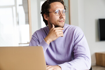 Attractive young man sitting at the kitchen table