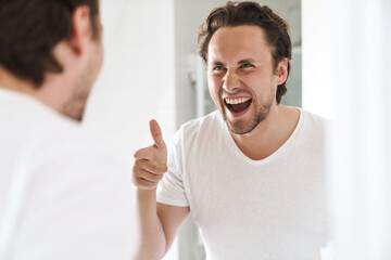 Attractive young man standing in front of the bathroom mirror