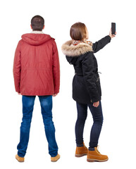 Back view of couple in winter jacket photographed on a mobile phone in winter jacket.