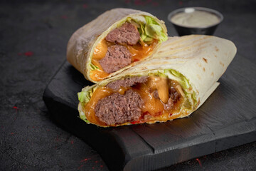 Wrap with beef, vegetables and sauce isolated on dark  background
