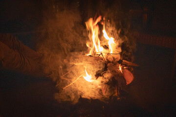 Horizontal nighttime shot of a campfire built on a small grill.