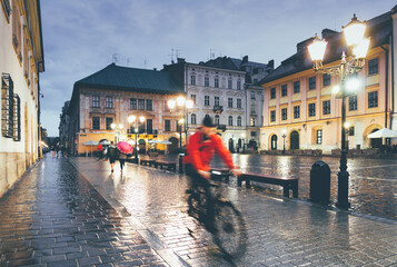 Biker in rain on cobblestone street in Krakow, Poland