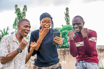 three black friends looking surprised and excited while looking at a mobile phone
