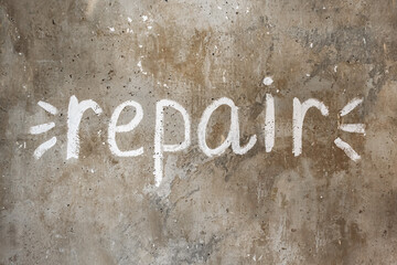 Text repair on an old wall, written in white paint.