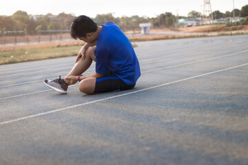 runner man injured after running. He is touching on ankle that is painful area.