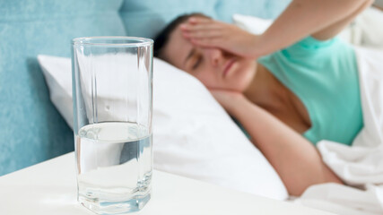 CLoseup image of sick young woman with headache lying in bed.