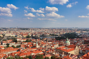 Fototapeta na wymiar view on the roofs of Prague, the capital of Czech Republic with cloudy blue sky in summer time from a high point in the middle you can see the Moldova 