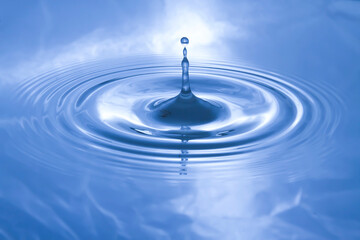 The water droplets fall on the water surface until the water spread out, creating beautiful ripples on the light blue water...