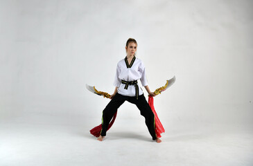 beautiful girl in a white and black suit does exercises with golden battle swords