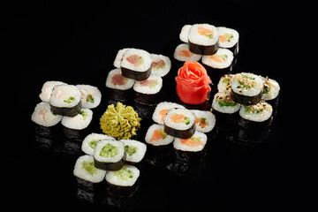 Japanese Cuisine - Appetizing Salmon Sushi Set. Philadelphia Sushi Roll - Maki Sushi with Philadelphia Cheese inside on mirror black background. Smoked salmon rolls served on a plate