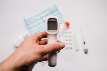 electronic thermometer in hand with medical mask