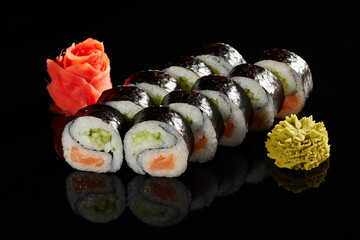 Japanese Cuisine - Appetizing Salmon Sushi Set. Philadelphia Sushi Roll - Maki Sushi with Philadelphia Cheese inside on mirror black background. Smoked salmon rolls served on a plate