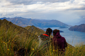 Couple overlooking on a cloudy day a lake on the top of Roys Peak mountain