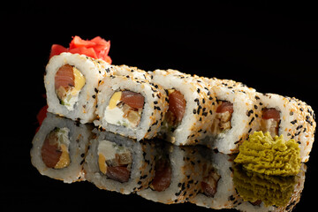 Japanese Cuisine - Appetizing Salmon Sushi Set. Philadelphia Sushi Roll - Maki Sushi with Philadelphia Cheese inside on mirror black background. Smoked salmon rolls served on a plate